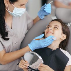 Igienista dentale visita una bambina sorridente sulla poltrona dello studio