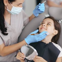 Igienista mostra il sorriso a una bambina con lo specchio dopo la visita
